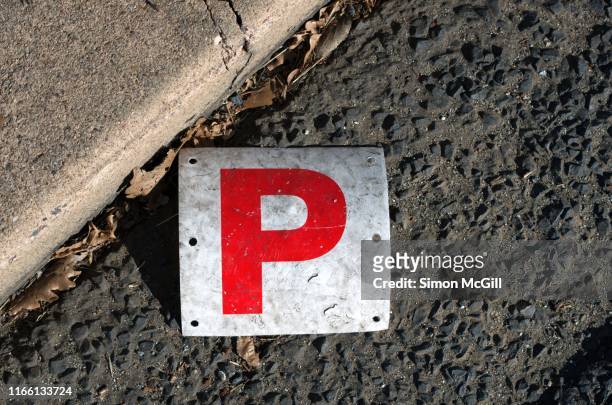 lost p plate laying by the kerb of an asphalt road - p stock-fotos und bilder