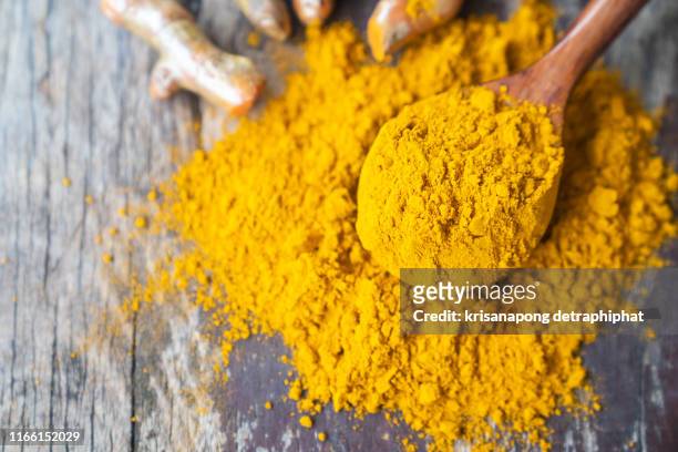 turmeric powder and fresh turmeric on wooden background. - orange powder ストックフォトと画像
