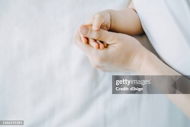 close up of mother holding baby's hand against white background - baby close up bed photos et images de collection