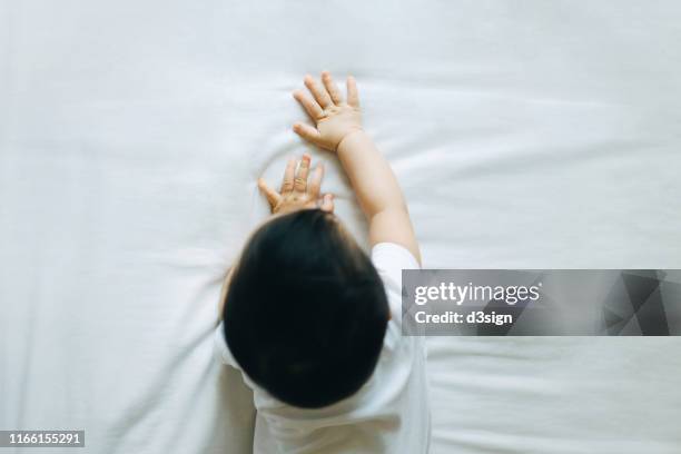 overhead view of cute asian baby crawling on bed and exploring - moments daily life from above imagens e fotografias de stock