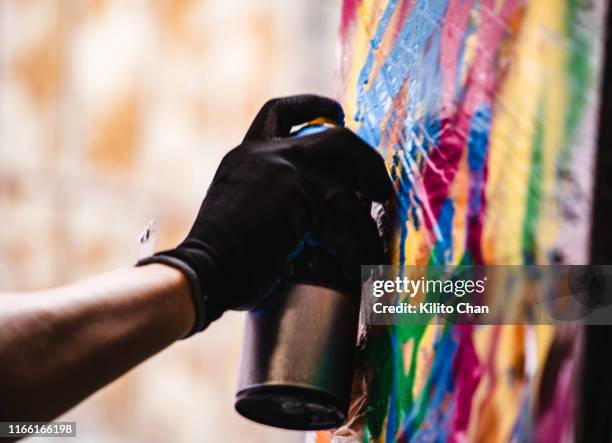 street artist making a spray graffiti on the wall - graffiti artists stock-fotos und bilder