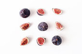 Fresh ripened purple figs. Creative square composition of the whole and sliced exotic fruit and isolated on white table background. Decorative pattern. Flat lay, top view from above. Food photography.