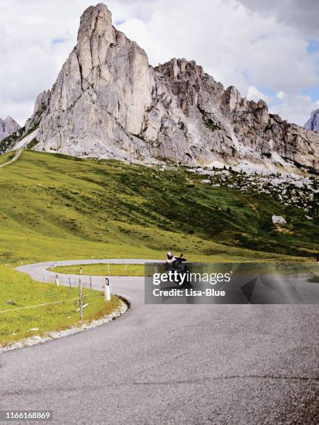 biker riding on mountain road in european alps - dirt road motorbike stock pictures, royalty-free photos & images