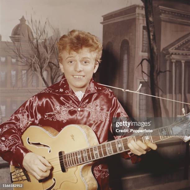 English rock and roll singer and entertainer Tommy Steele posed playing his Hofner semi acoustic guitar car in September 1957.