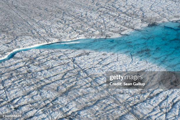 In this view from an airplane a lake of meltwater feeds a canal the meltwater has carved into the Greenland ice sheet near Sermeq Avangnardleq...