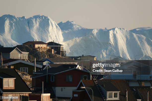 Icebergs in the Ilulissat Icefjord loom behind buildings on August 04, 2019 in Ilulissat, Greenland. The Sahara heat wave that recently sent...