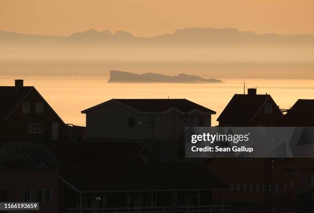 An iceberg floats in Disko Bay at sunset behind houses on August 04, 2019 at Ilulissat, Greenland. The Sahara heat wave that recently sent...