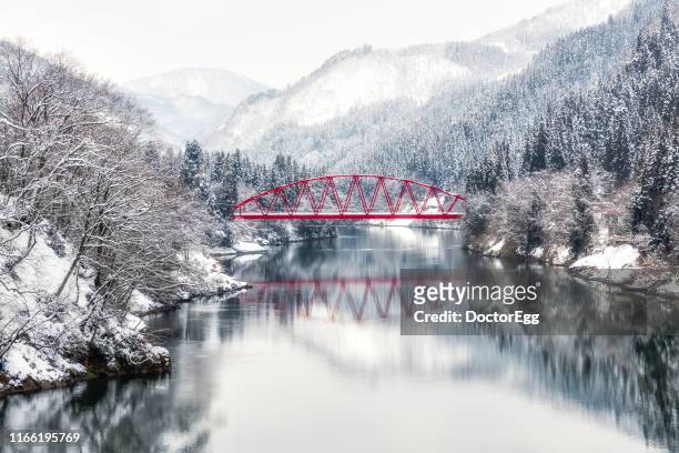 red bridge across tadami river in winter near aizu miyashita station , mishima, fukushima, japan - japan winter stock pictures, royalty-free photos & images