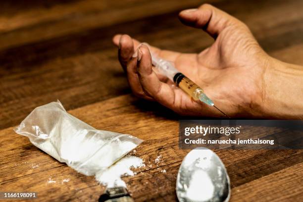 drug addict hand with syringe on the floor with a bag of drugs a spoon and a lighter. drugs concept,  anti drug concept. - heroin stock-fotos und bilder