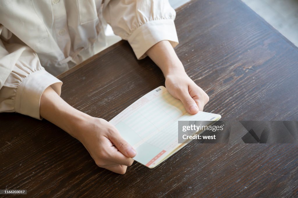 Young woman trying to open a passbook on a desk
