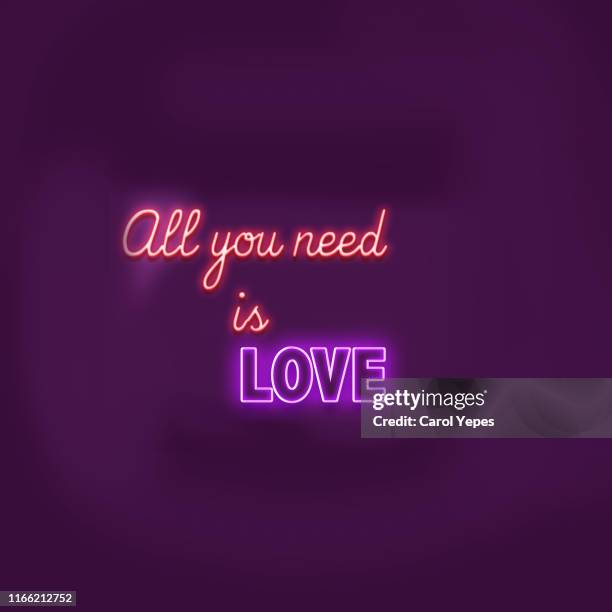 all you need is love  text  neon sign in brick wall - love letter stockfoto's en -beelden