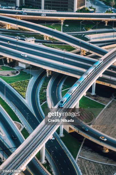 highway intersection and metro train in dubai, uae - dubai metro stock pictures, royalty-free photos & images
