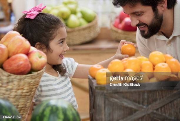 father and daughter buying fruits at supermarket - kidstock girl stock pictures, royalty-free photos & images