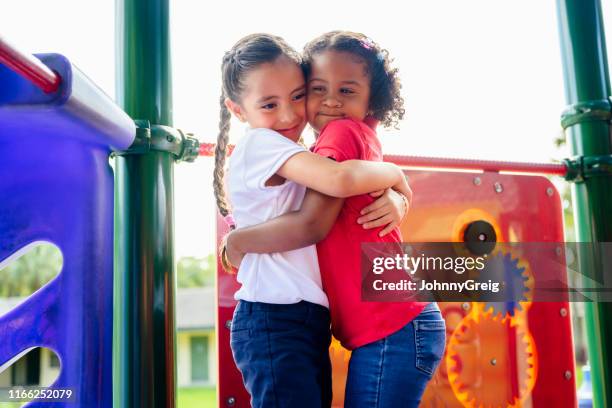 elementary aged hispanic best friends hugging on playground - affectionate gesture stock pictures, royalty-free photos & images