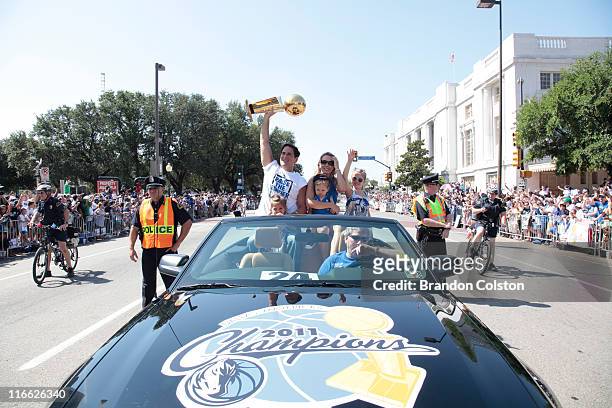 Mark Cuban, owner of the Dallas Mavericks holds the Larry O'Brien trophy above his head as he and his family ride along during the Mavericks NBA...