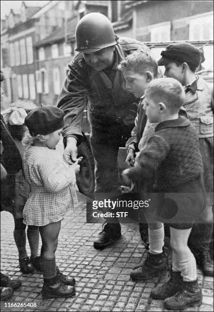 Un soldat américain offre des bonbons à des enfants français, à Sarreguemines, dans le nord de la France, en 1945, durant une permission de quelques...