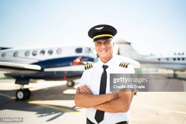 portrait of airplane pilot in front of a private jet and looking at camera - civil aviation stock pictures, royalty-free photos & images