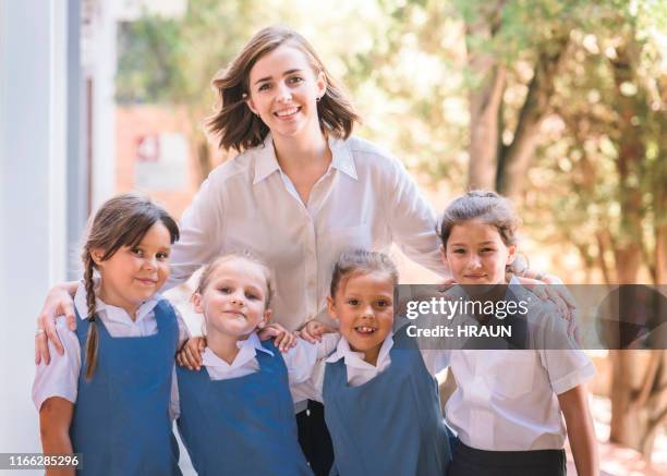 ritratto di insegnante sorridente con studentesse a scuola - maestra foto e immagini stock