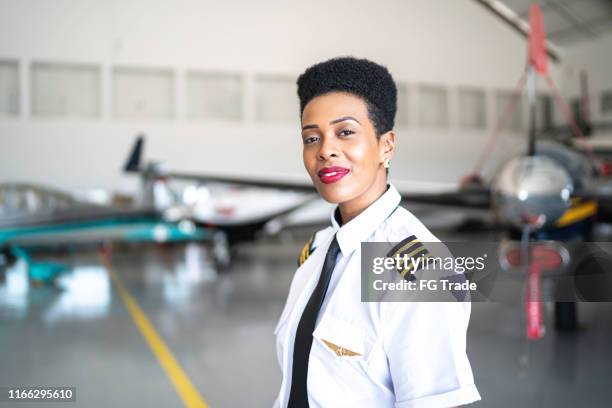 portrait of airplane pilot in a hangar and looking at camera - airline pilot imagens e fotografias de stock