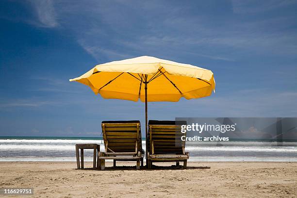 sun chairs with yellow umbrella - beach umbrella isolated stockfoto's en -beelden
