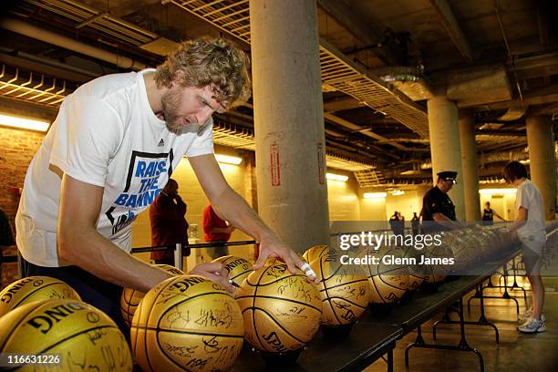 Dirk Nowitzki of the Dallas Mavericks signs special edition "Champions" basketballs during the Mavericks NBA Champion Victory Parade on June 16, 2011...