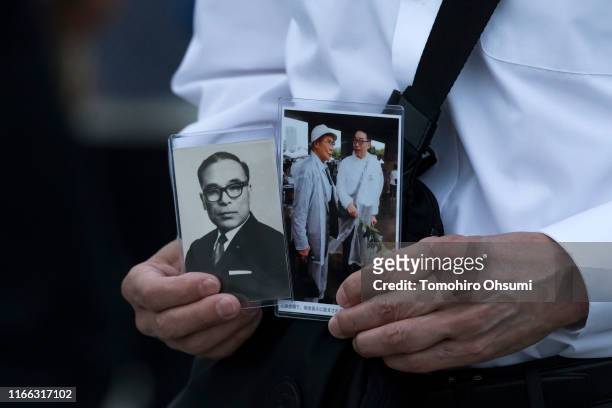 Man holds photographs as he prays on the 74th anniversary of the atomic bombing of Hiroshima at the Hiroshima Peace Memorial Park on August 6, 2019...