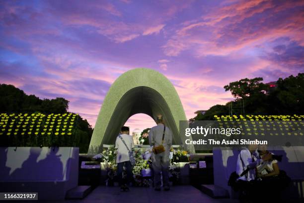 People pray for the victims in front of the cenotaph on the 74th anniversary of the atomic bombing of Hiroshima at the Hiroshima Peace Memorial Park...