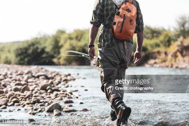 fly fisherman walking in the river, wyoming, united states - waders imagens e fotografias de stock