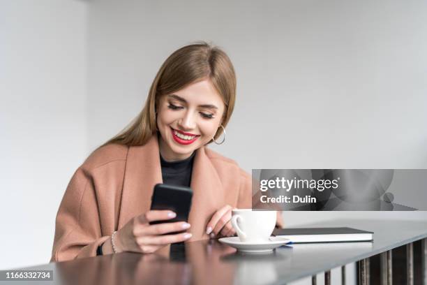 smiling woman looking at her mobile phone - vogues forces of fashion conference stockfoto's en -beelden