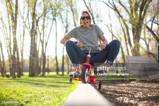 woman playing on tricycle in the park, united states - tricycle stock-fotos und bilder