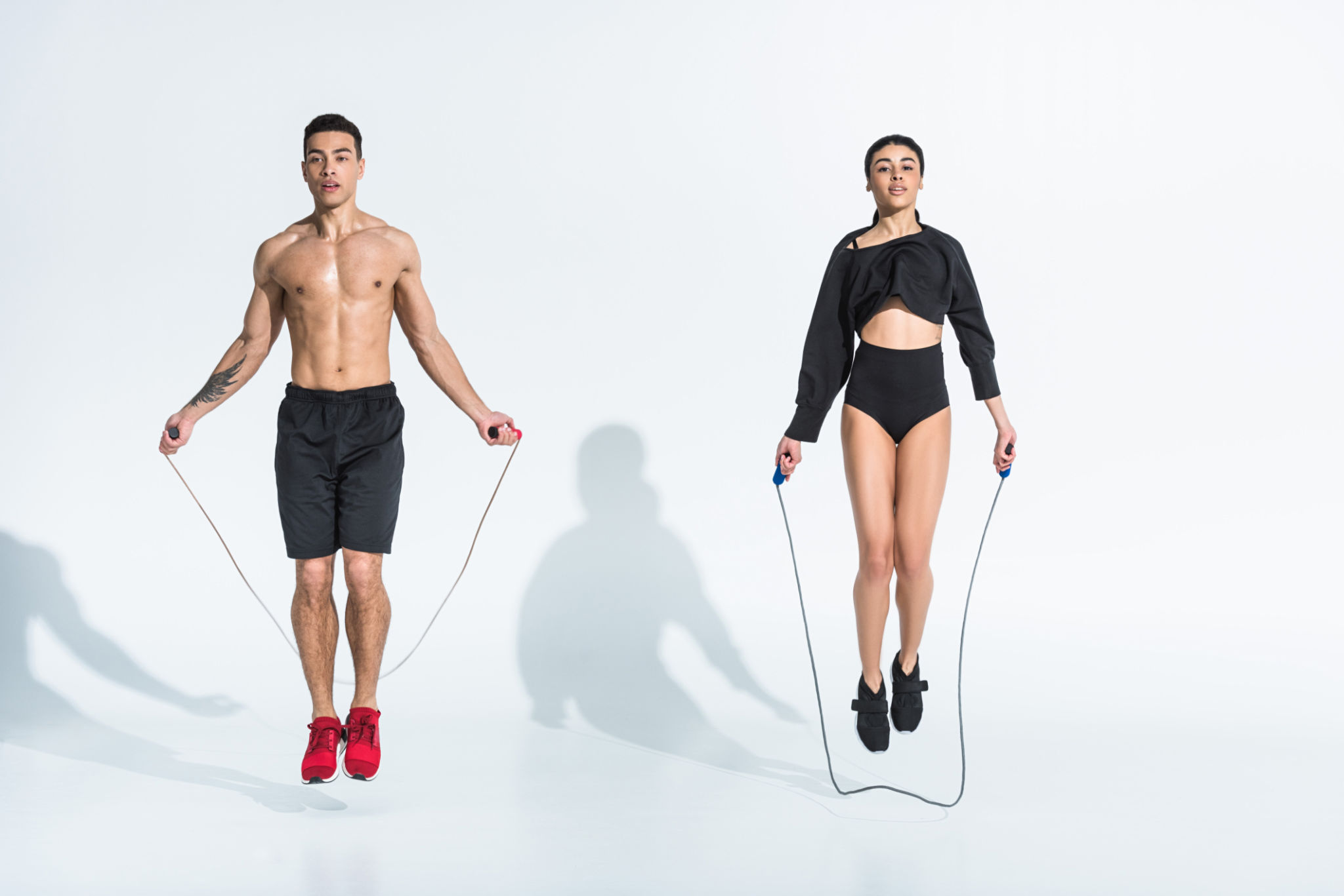 sportive multicultural man and woman jumping with skipping ropes sportive multicultural man and woman jumping with skipping ropes