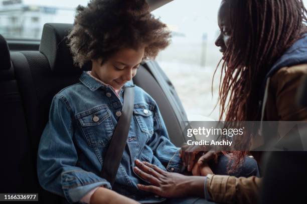 madre che si allaccia al bambino sul seggiolino di sicurezza dell'auto - cintura foto e immagini stock