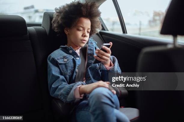 little girl using smartphone while traveling in car - comfortable car stock pictures, royalty-free photos & images