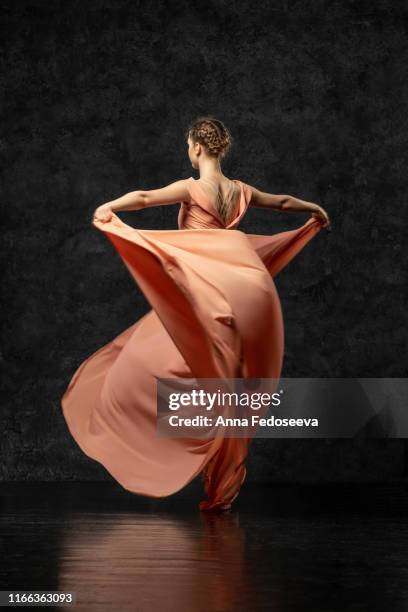 ballerina. a young dancer dressed in a long peach dress, pointe shoes with ribbons. performs a graceful, graceful dance movement  which is visible from the back. beautiful classic ballet. - woman fashion long dress stock pictures, royalty-free photos & images