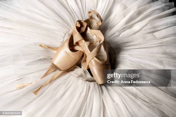 pointe shoes. peach shoes, ballet shoes with ribbons on a white tutu in a dance studio. advertising ballet school. professional ballerina outfit. - ballettschuh stock-fotos und bilder