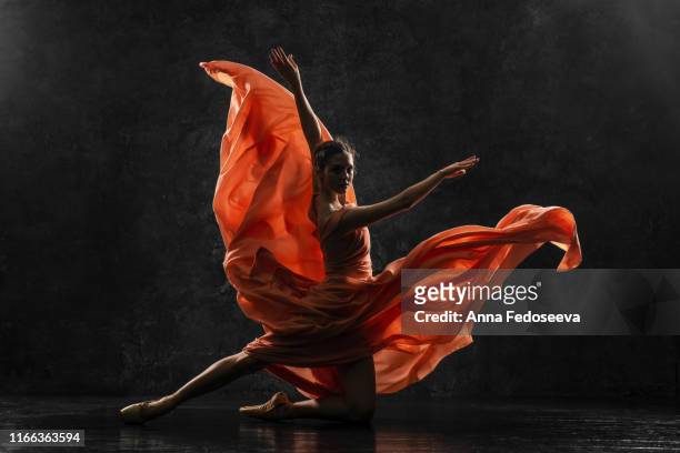 ballerina. silhouette photo of a young  ballet dancer dressed in a long peach dress, pointe shoes with ribbons. the girl performs an graceful dance movement. beautiful classic ballet. ballet studios. - performance stock-fotos und bilder