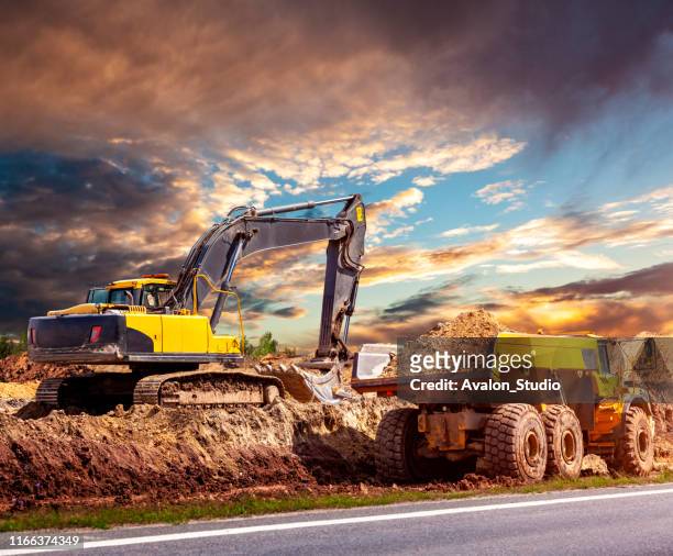 graafmachine en dump truck op de bouwplaats - shovel stockfoto's en -beelden