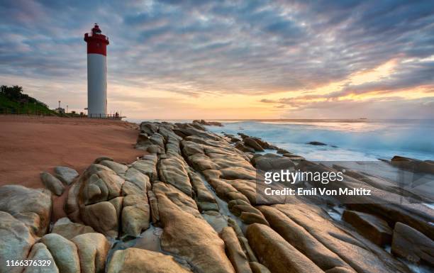 an early morning picturesque stratocumulus sky of the iconic umhlanga rocks lighthouse and waves rolling onto the rocks on the shore. durban, kwazulu-natal natal, south africa - durban fotografías e imágenes de stock