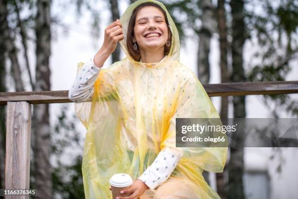girl teenager outdoors dressed in a raincoat with a paper cup in her hands - girl face hat raincoat stock pictures, royalty-free photos & images