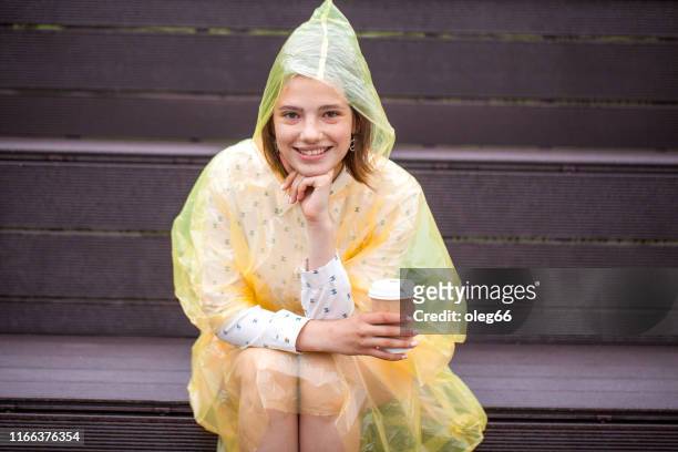 girl teenager outdoors dressed in a raincoat with a paper cup in her hands - girl face hat raincoat stock pictures, royalty-free photos & images