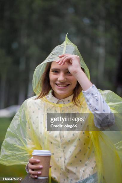 girl teenager outdoors dressed in a raincoat with a paper cup in her hands - girl face hat raincoat stock pictures, royalty-free photos & images