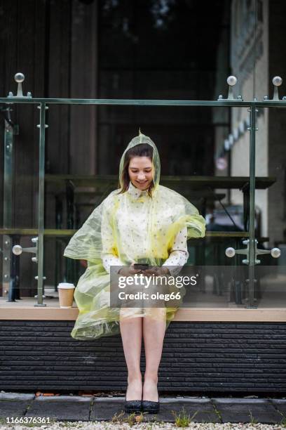 girl teenager outdoors dressed in a raincoat with a paper cup in her hands - girl face hat raincoat stock pictures, royalty-free photos & images