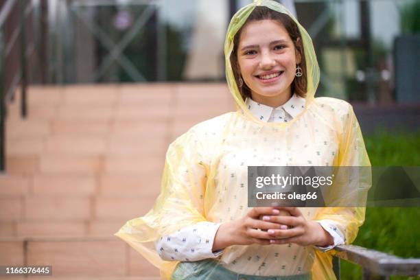 girl teenager outdoors dressed in a raincoat with a paper cup in her hands - girl face hat raincoat stock pictures, royalty-free photos & images