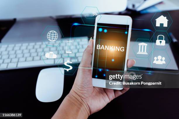 businessman holding smart phone use word banking in hand with icon network connection on virtual screen dark background - bank manager photos et images de collection