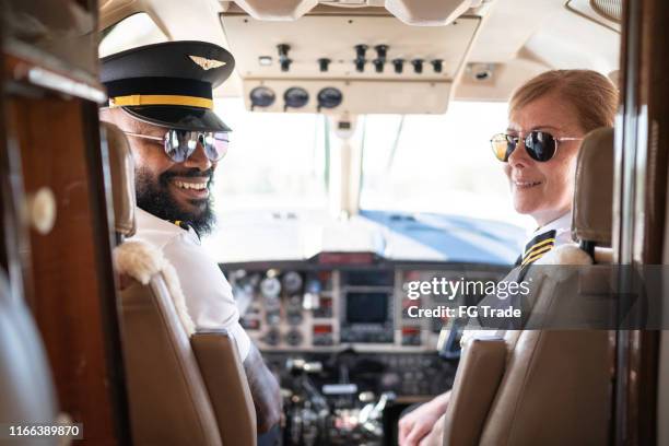 retrato de dos pilotos de avión mirando por encima del hombro en un jet privado - pilot fotografías e imágenes de stock