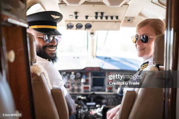 portrait of two airplane pilots looking over shoulder in a private jet - pilote stock pictures, royalty-free photos & images