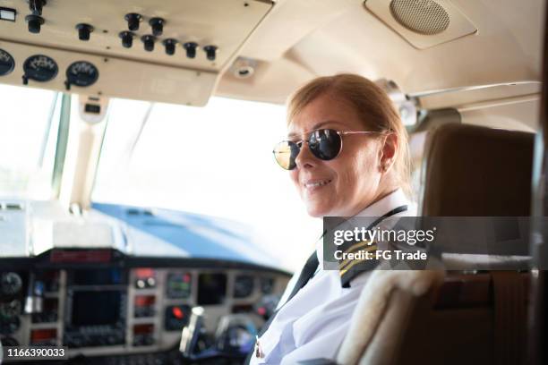 porträt des flugzeugpiloten, der in einem privatjet über die schulter schaut - female pilot stock-fotos und bilder