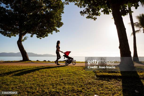 silhouette of a mother pushing a carriage at the beach - mum pushing pram stock-fotos und bilder