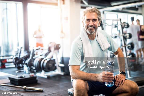 mature man taking a break from exercise in a health club. - after workout towel happy stock pictures, royalty-free photos & images