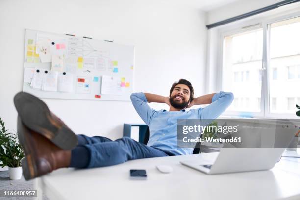 smiling businessman relaxing at a desk - bending over backwards stock pictures, royalty-free photos & images